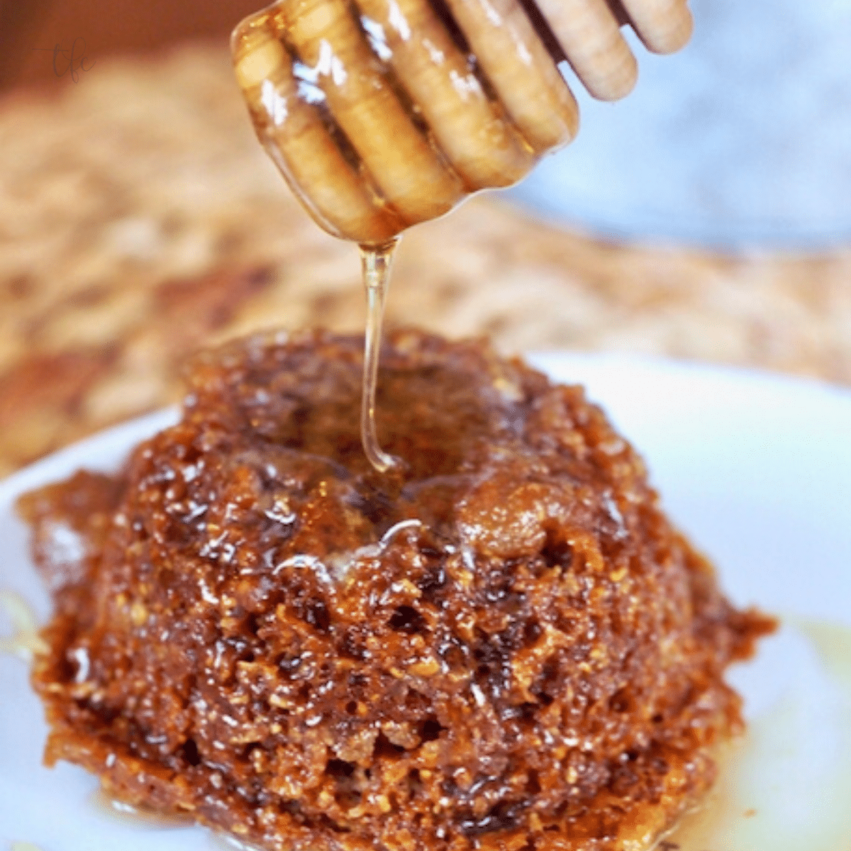 Mimi's Copycat Honey Bran Muffin with muffin on plate and honey stick dripping fresh honey on hot muffin.