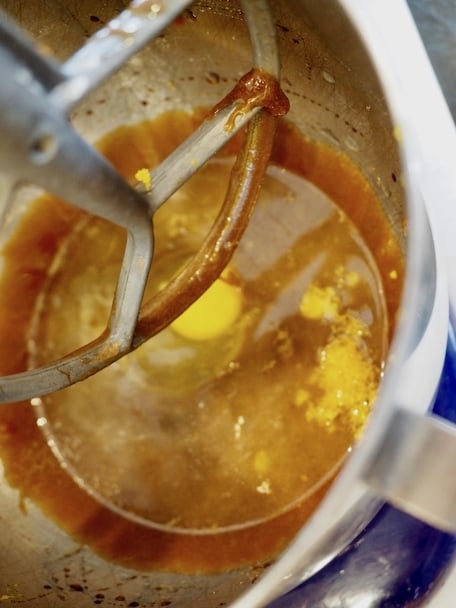In stainless bowl of stand mixer adding egg, water, cream, and orange zest.
