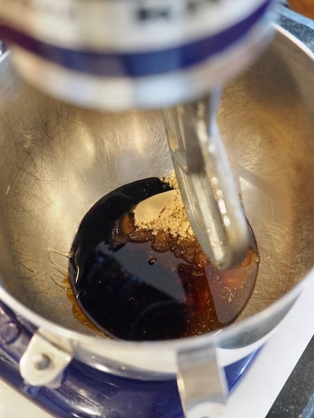 Looking into a stainless bowl of Kitchenaid stand mixer at honey, brown sugar mixture. 