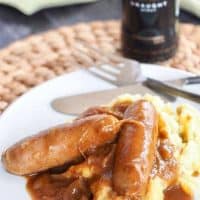 Bangers (Sausages) and mash with stout onion gravy and Guinness in background.