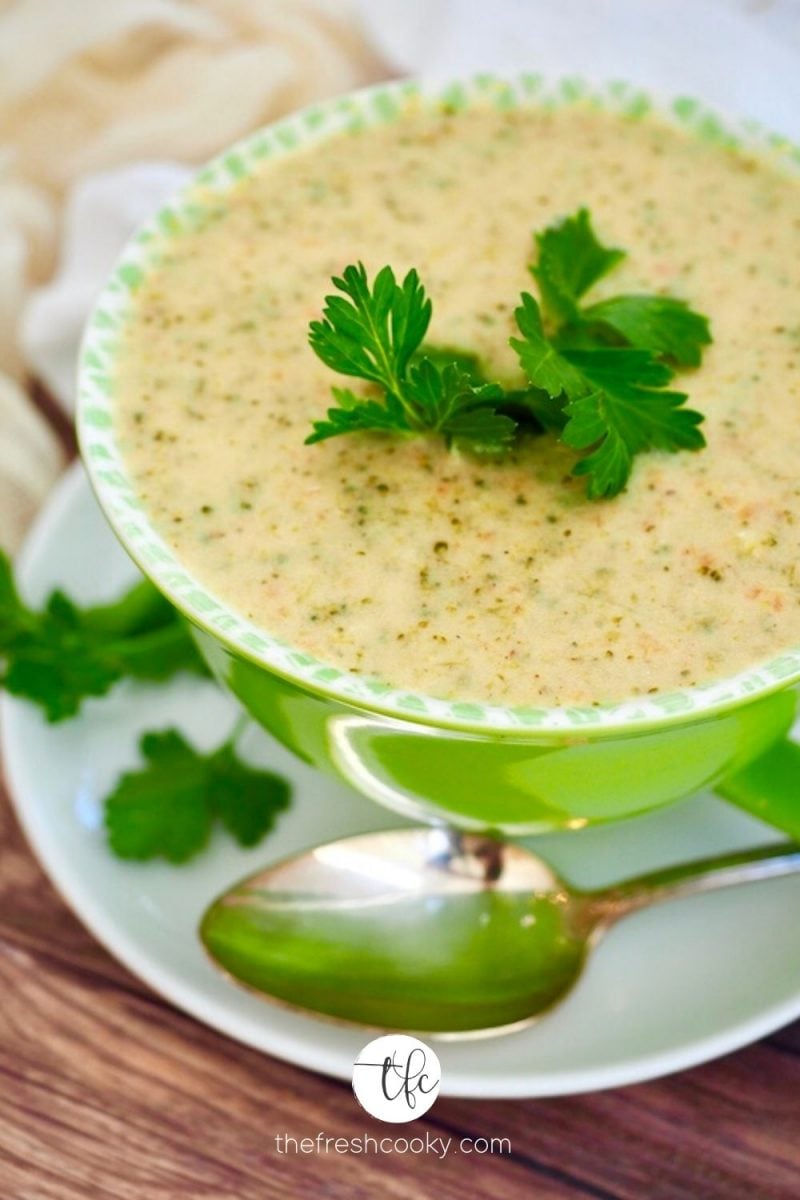 Top down image of large bright green bowl filled with creamy broccoli cheese copycat Panera soup.