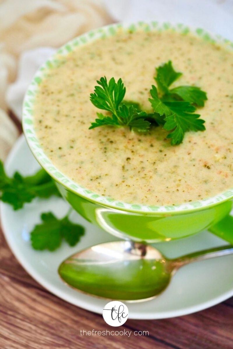 Top down image of large bright green bowl filled with creamy broccoli cheese copycat Panera soup. 