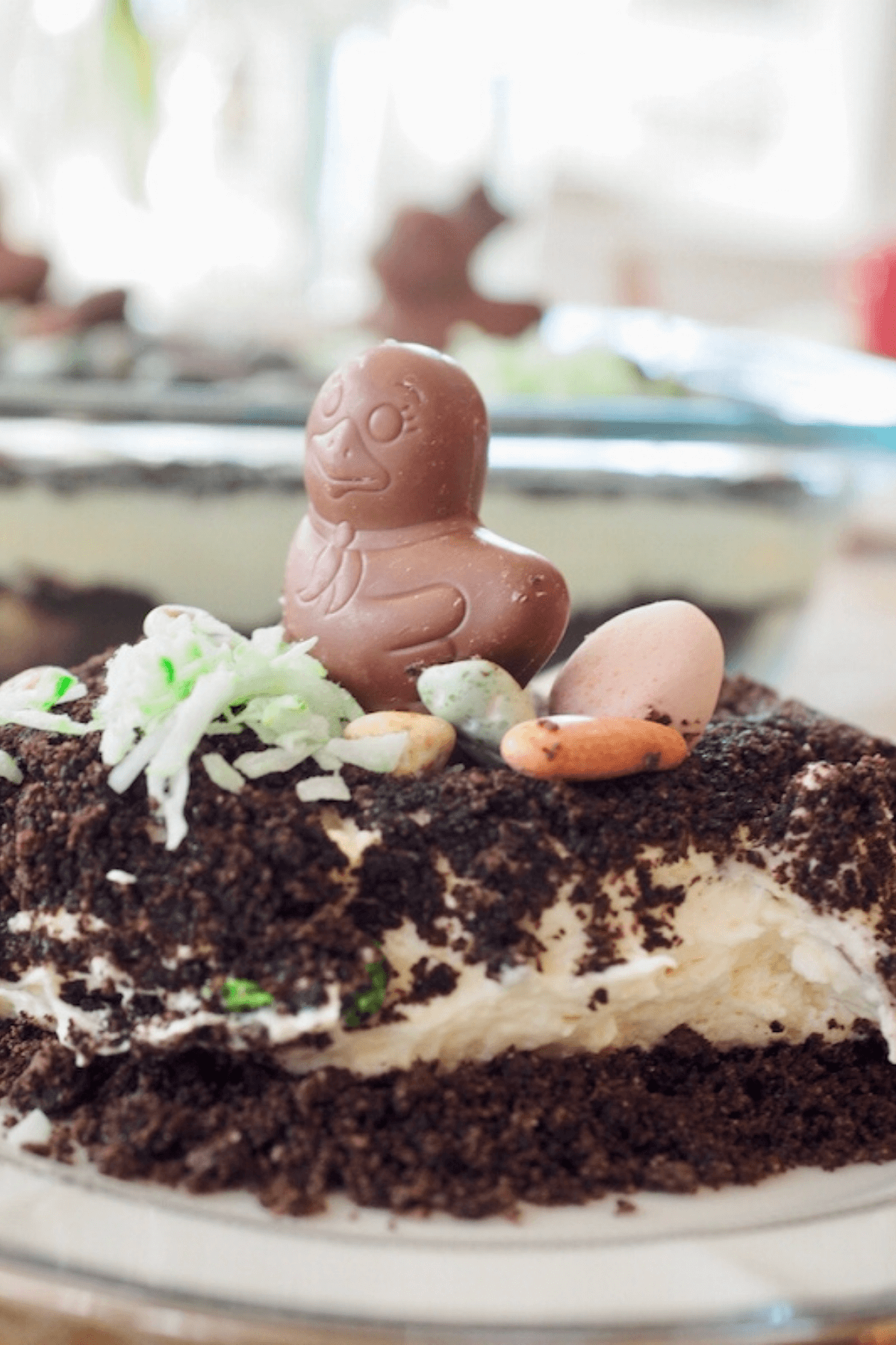 Easter Dirt Cake recipe image with slice on plate with chocolate chick on top.
