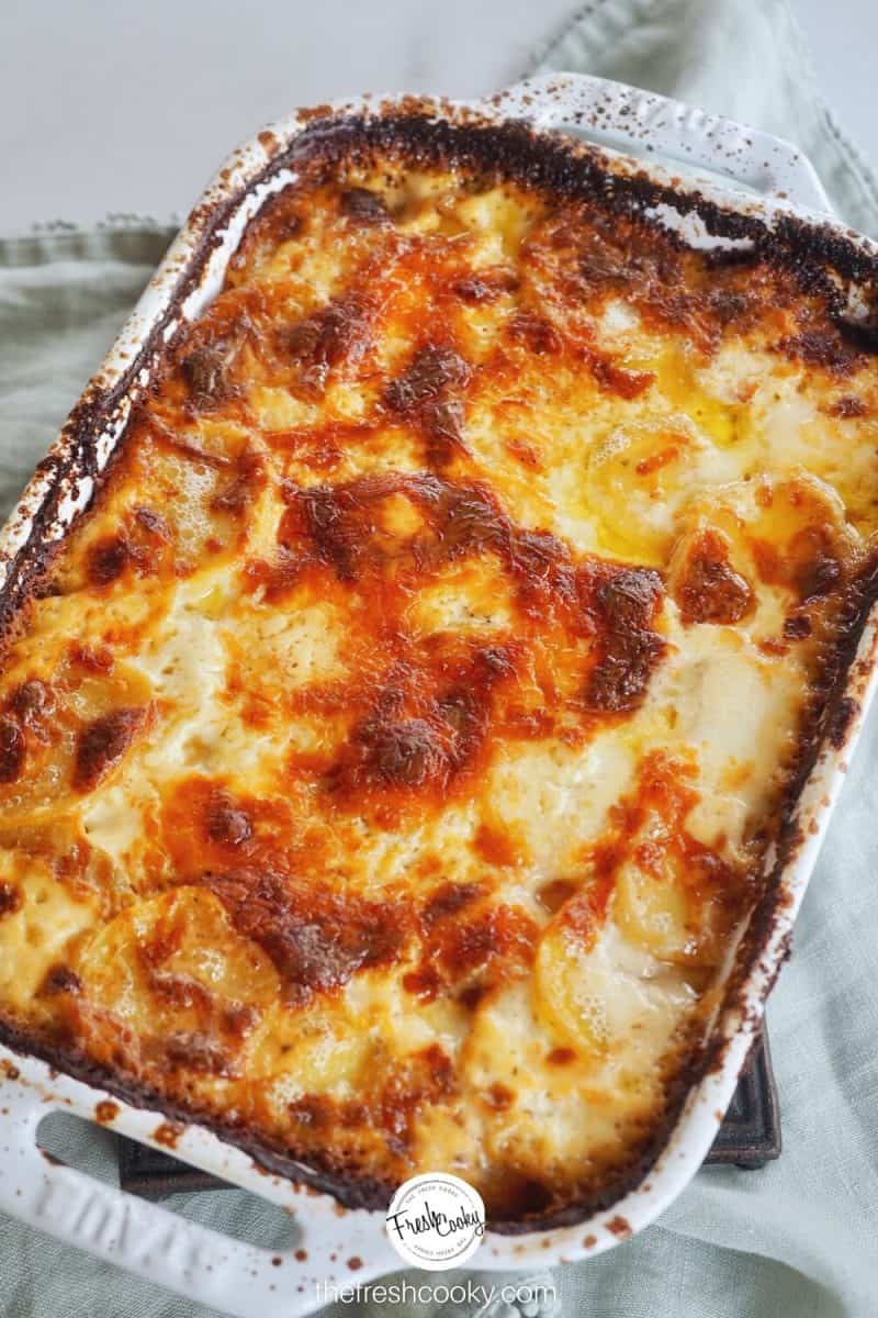 Image of baked golden brown casserole of potatoes gratin gruyere in white ceramic baking dish