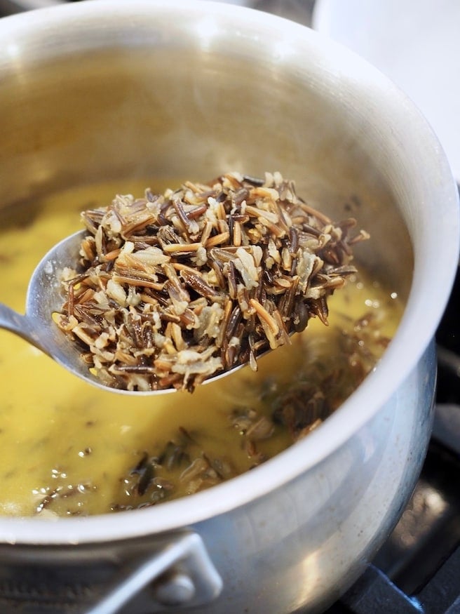wild rice on slotted spoon in pot with broth.