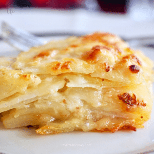 Square Image of slice of potatoes au gratin, with layers of creamy, gruyere cheesy deliciousness.
