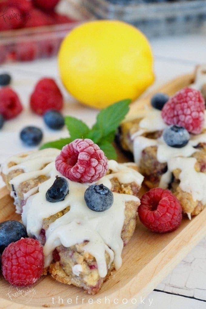 Glazed Raspberry Blueberry Scones close up with frozen berries and mint.
