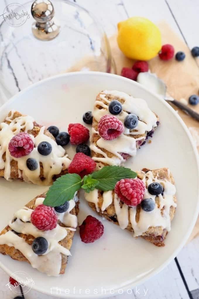Glazed Raspberry Blueberry Scones on plate with fresh berries.