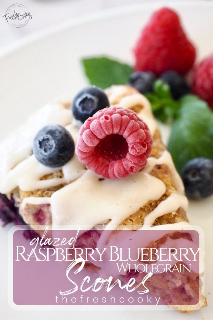 Glazed Raspberry Blueberry Scones on plate with frozen raspberry and blueberries on top. 
