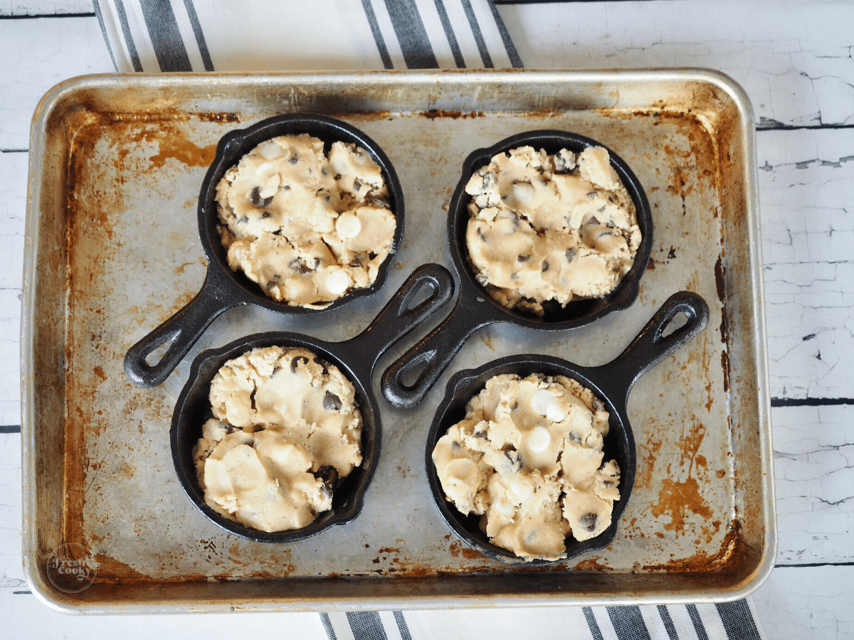 Mini Cast Iron Skillet Chocolate Chip Cookie Recipe with dough pressed into mini skillets on cookie sheet.