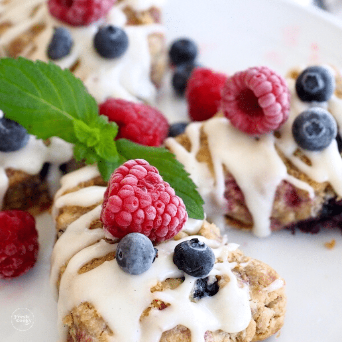 Mixed Berry Scones on a plate with fresh raspberries and blueberries on top, square image.