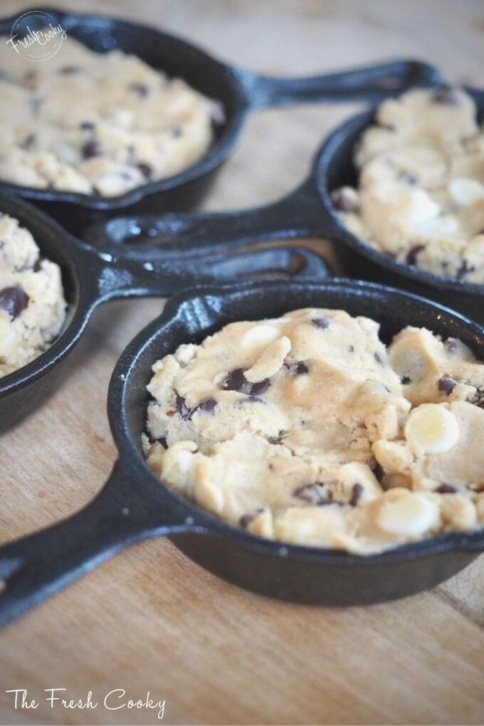 Close up of half baked cookie dough in mini cast iron skillets ready for oven. 