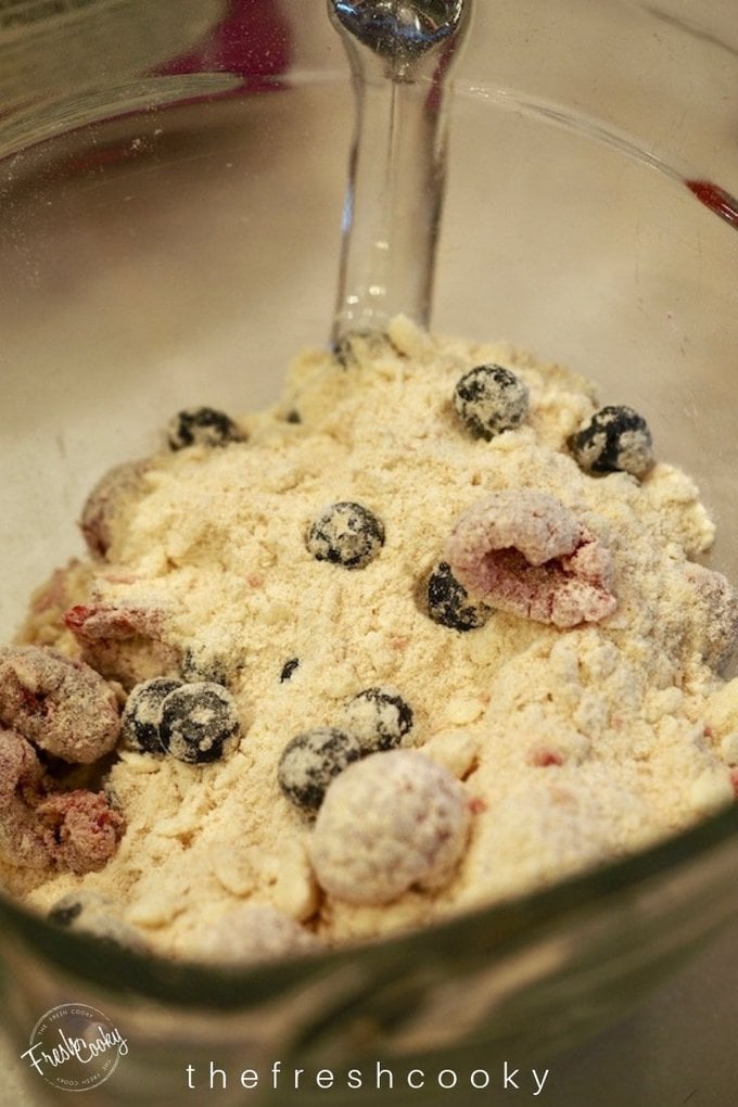 Stirring in raspberries and blueberries into scone mixture for Glazed Raspberry Blueberry Scones.