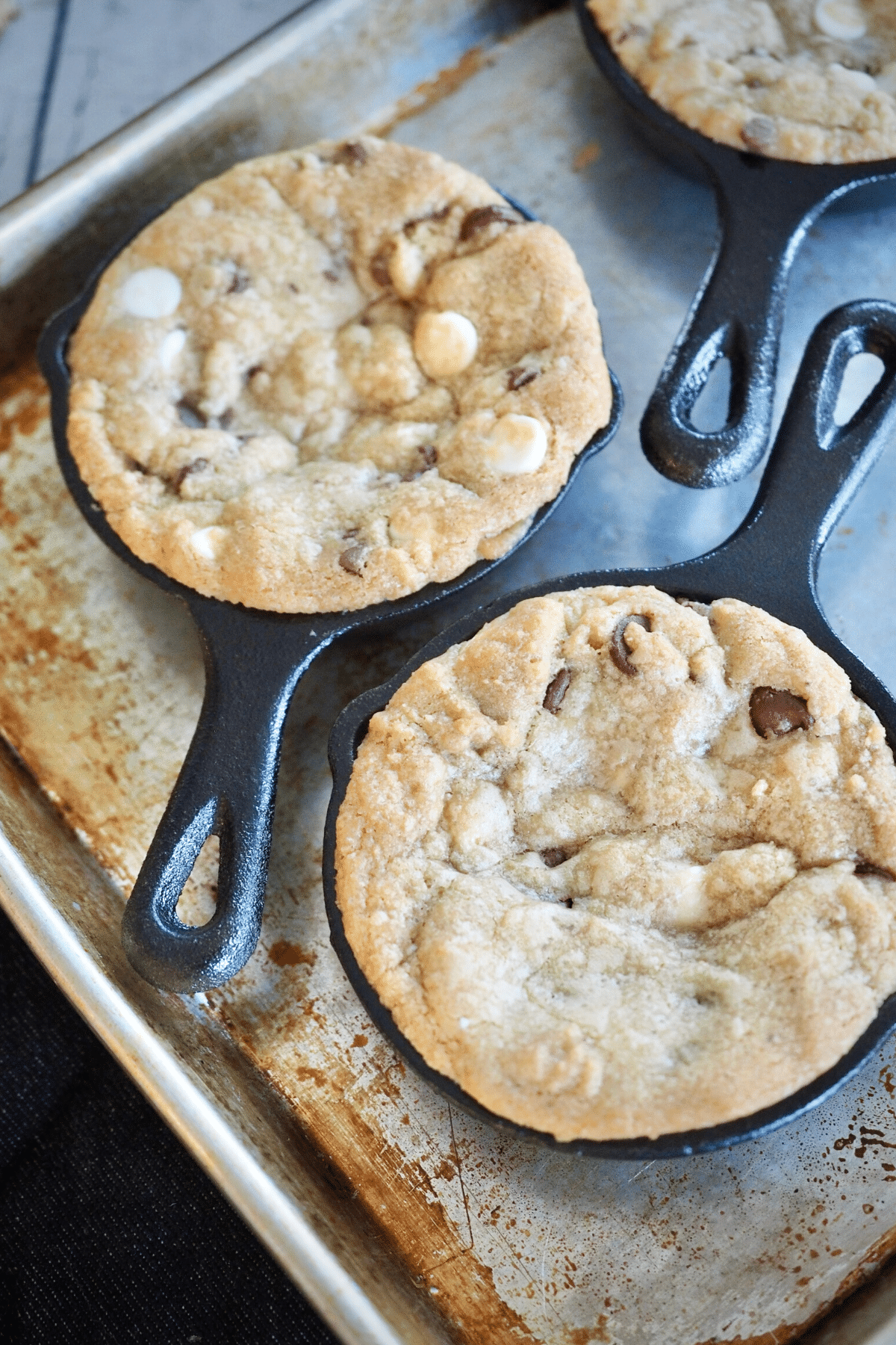 Half baked cookie in mini cast iron skillets on cookie sheet. 