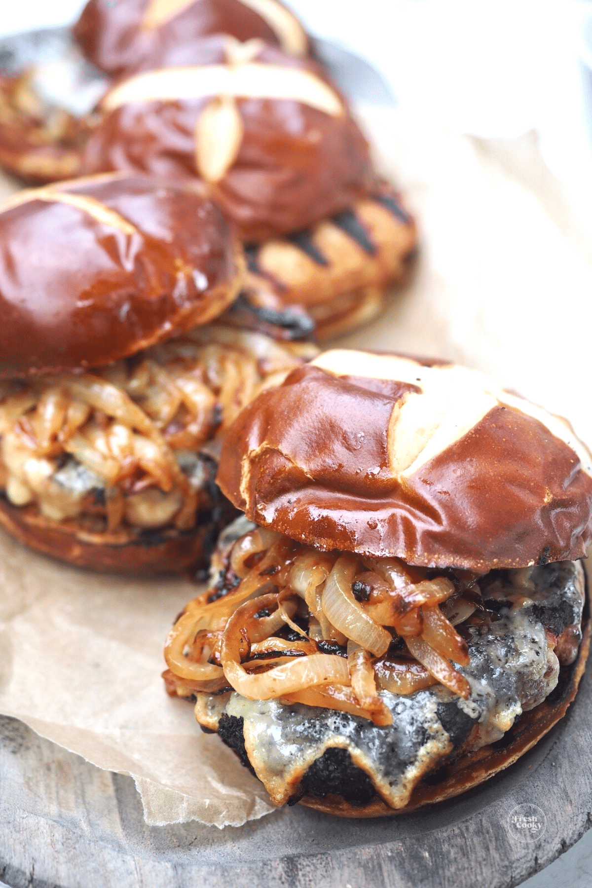 Juicy burgers with onions lined up on a tray.