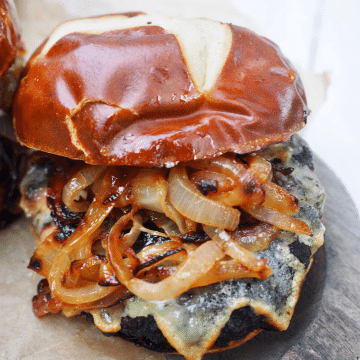 Juicy bison burger with melted juice and caramelized onions on pretzel rolls.