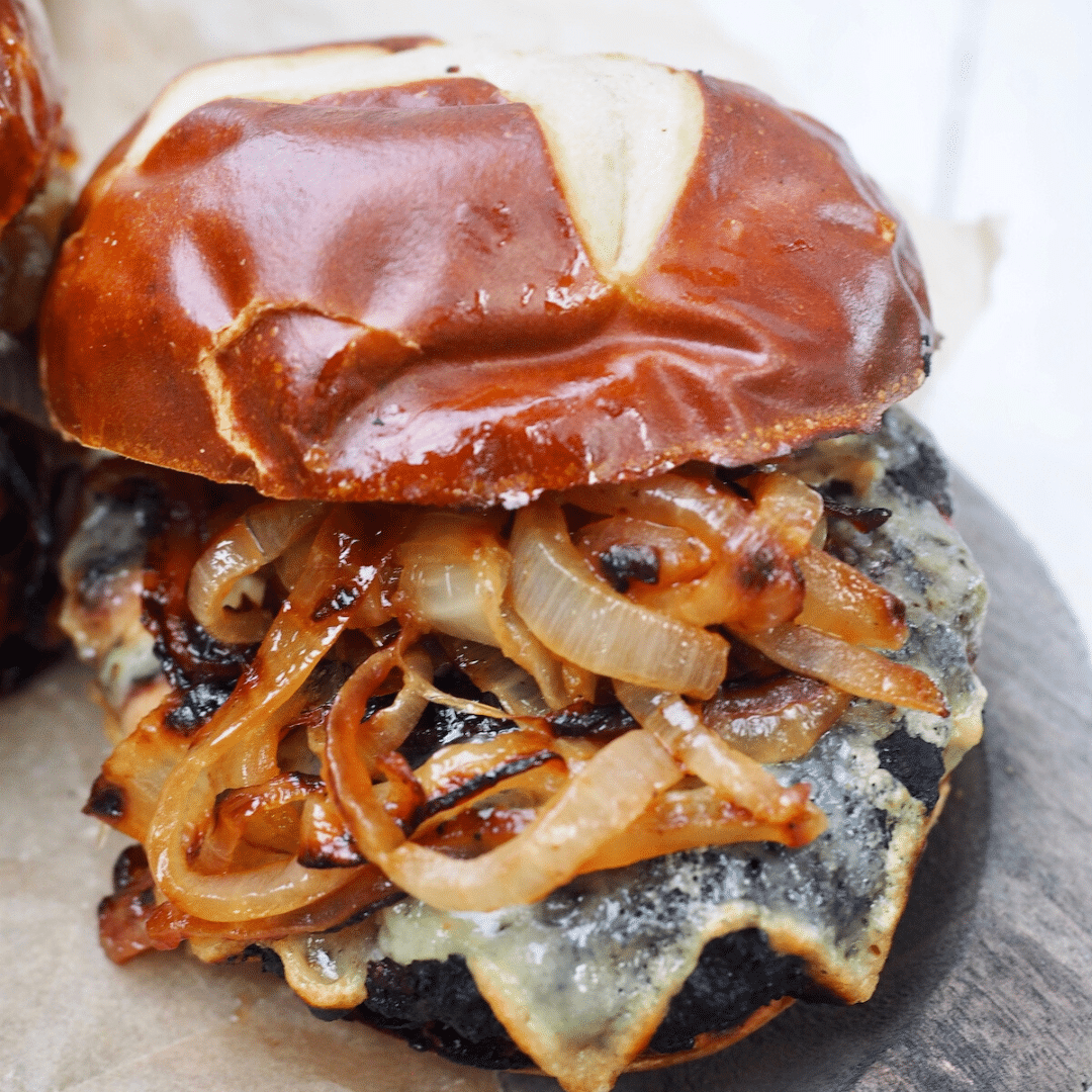 Juicy bison burger with melted juice and caramelized onions on pretzel rolls.