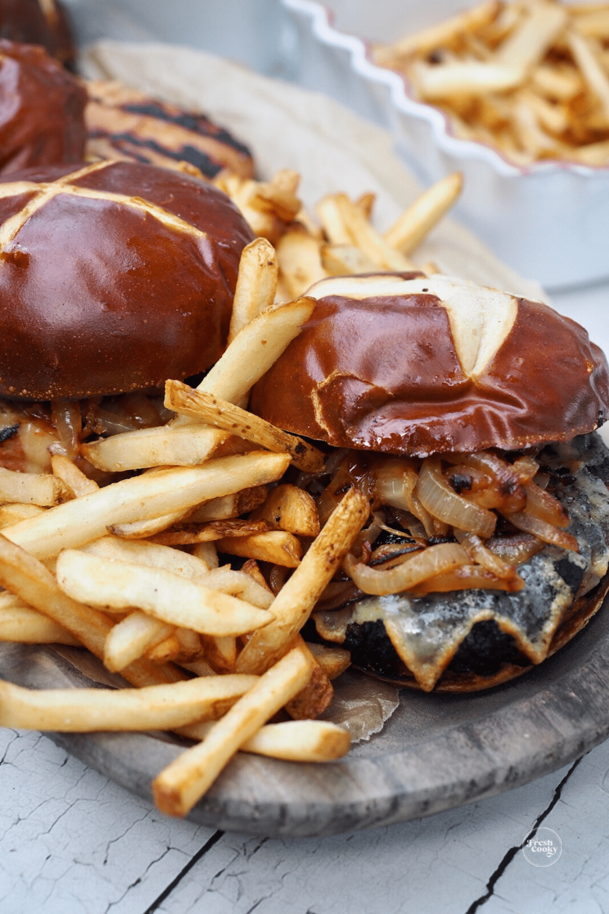 Juicy bison burger with french fries and another burger in the background.