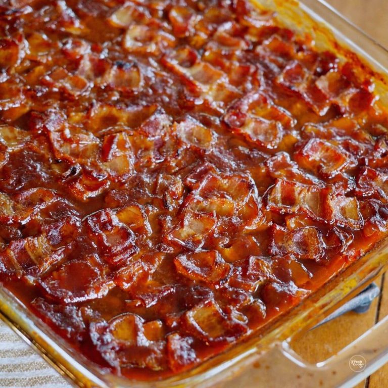 Cowboy baked beans in glass dish with crispy bacon.