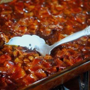 Cowboy baked beans in pan with spoon.