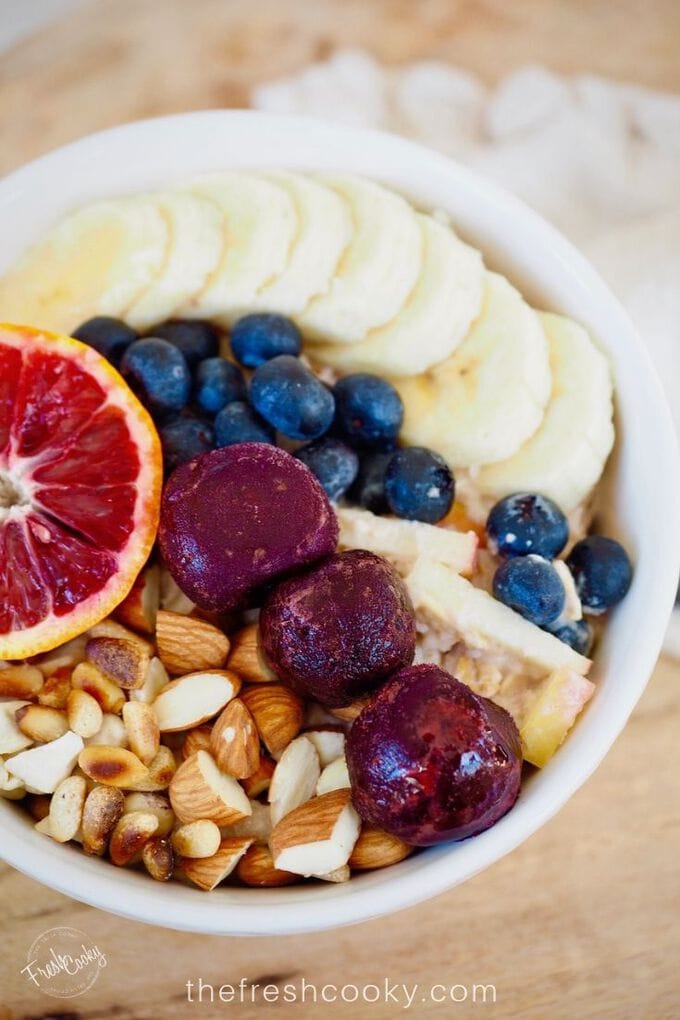 Image of pretty bowl filled with protein overnight oats, or bircher Swiss muesli, topped with nuts, fruit, berries and bananas.