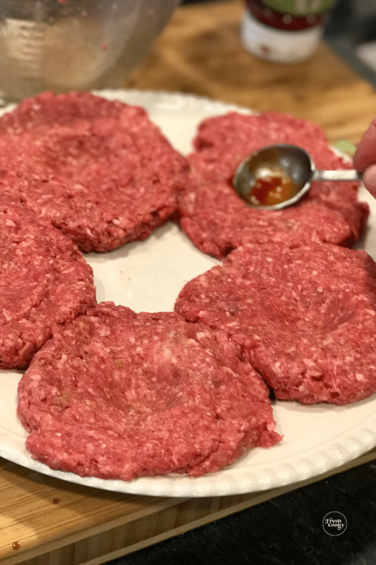 Pressing wells into center of burgers with tablespoon.