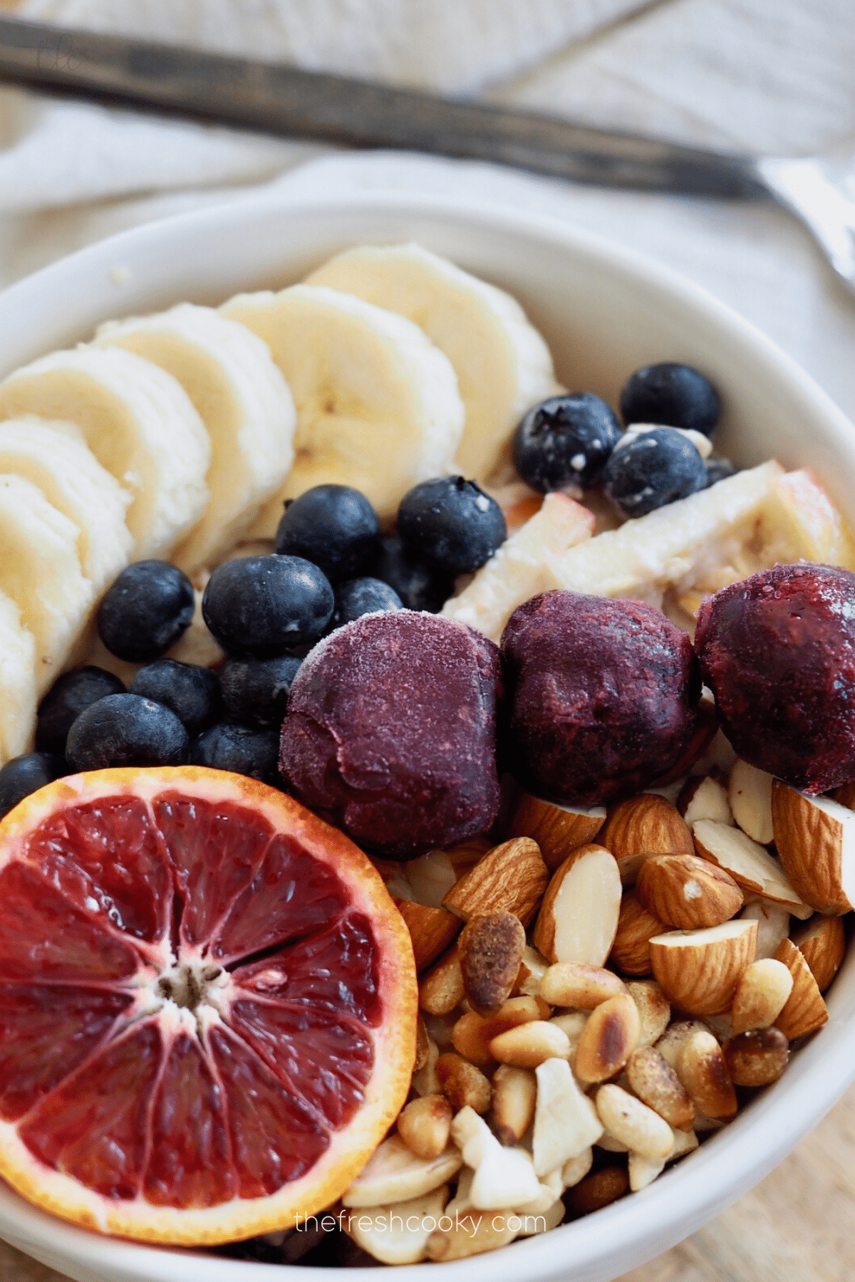 Close up of a bowl filled with protein overnight oats, fruit, berries and nuts.