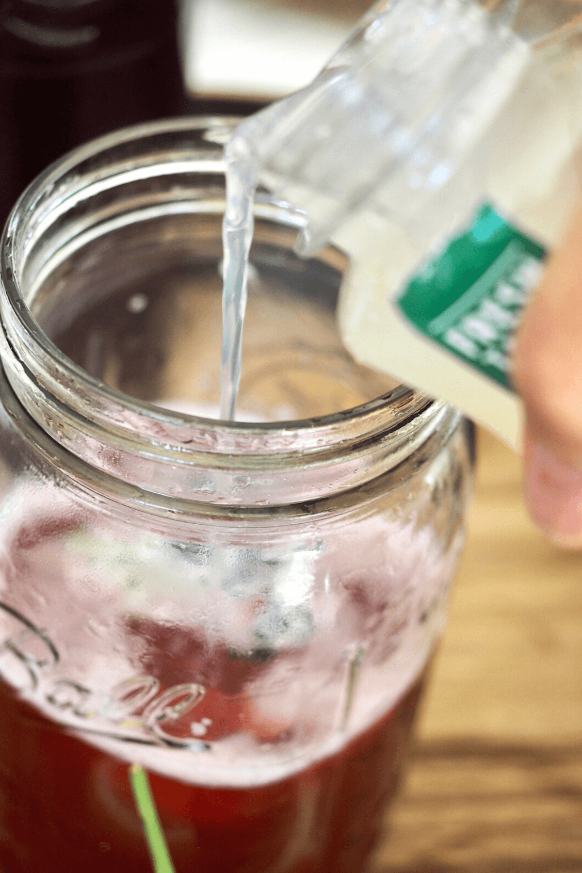 Pouring lemonade into jar with concentrate to make passion tea lemonade. 