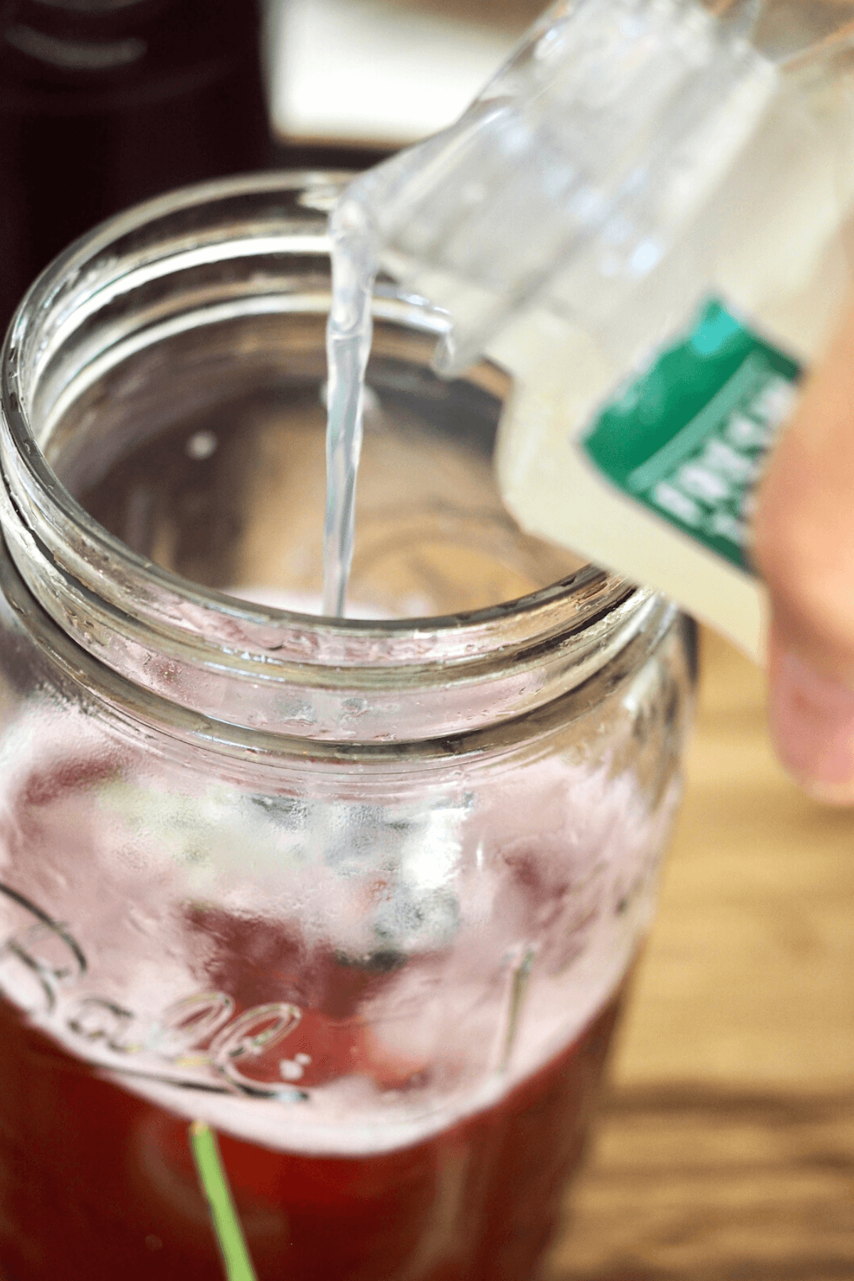 Pouring lemonade into jar with concentrate to make passion tea lemonade.