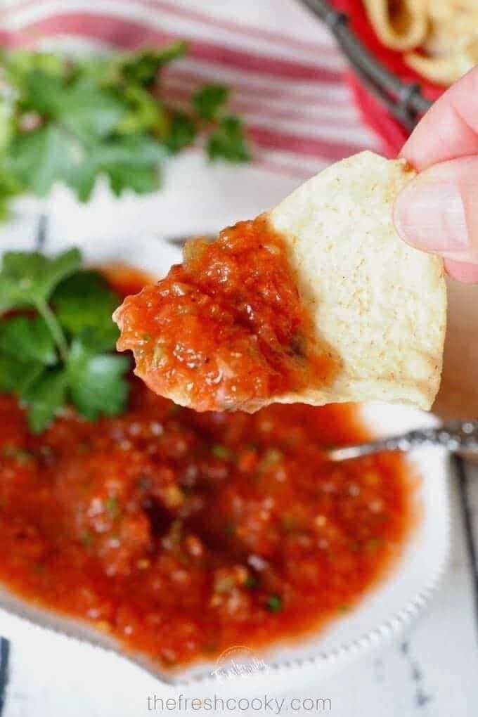 Blender salsa in a bowl, with a tortilla chip dipped in.