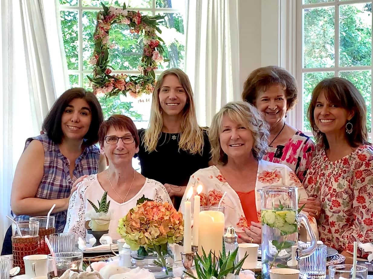 Me and my sisters-in-law at the table for my mom's birthday celebration, pretty table set with candles and flowers. 