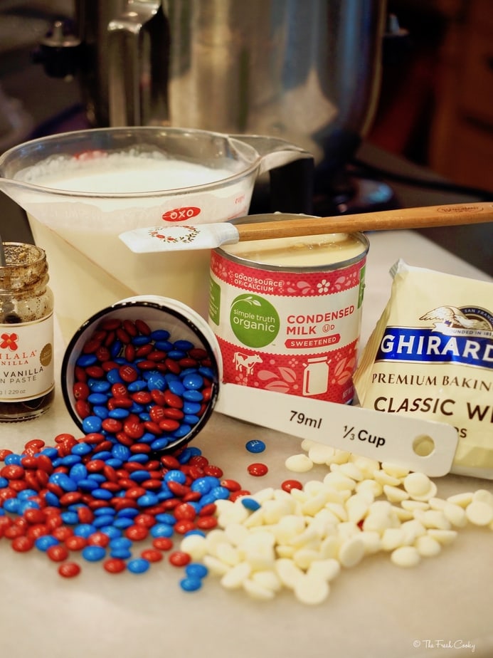 Ingredients for No Churn Patriotic Ice Cream L-R vanilla bean paste, organic sweetened condensed milk, Ghirardelli white chocolate chips, Heavy whipping cream and red and blue mini M&M's.