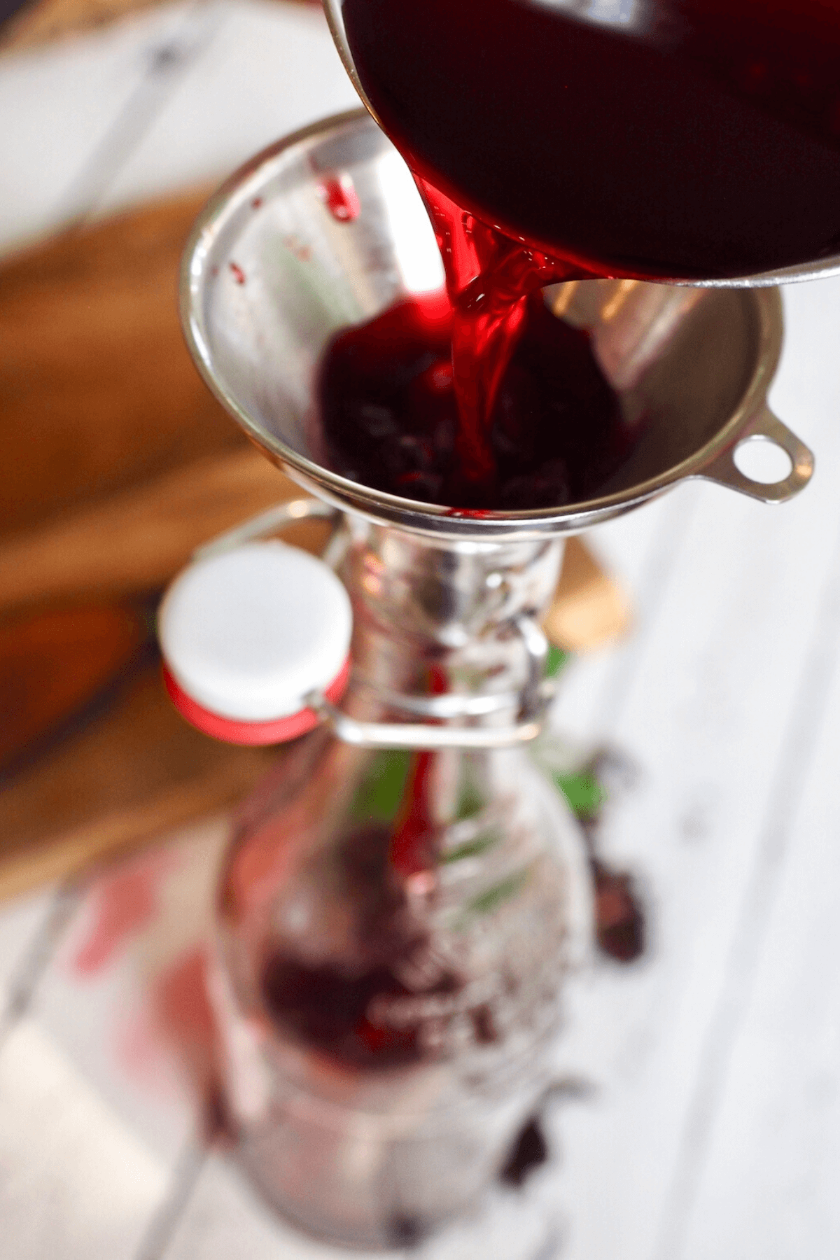 Pouring cooled passion tea concentrate through funnel into bottle.