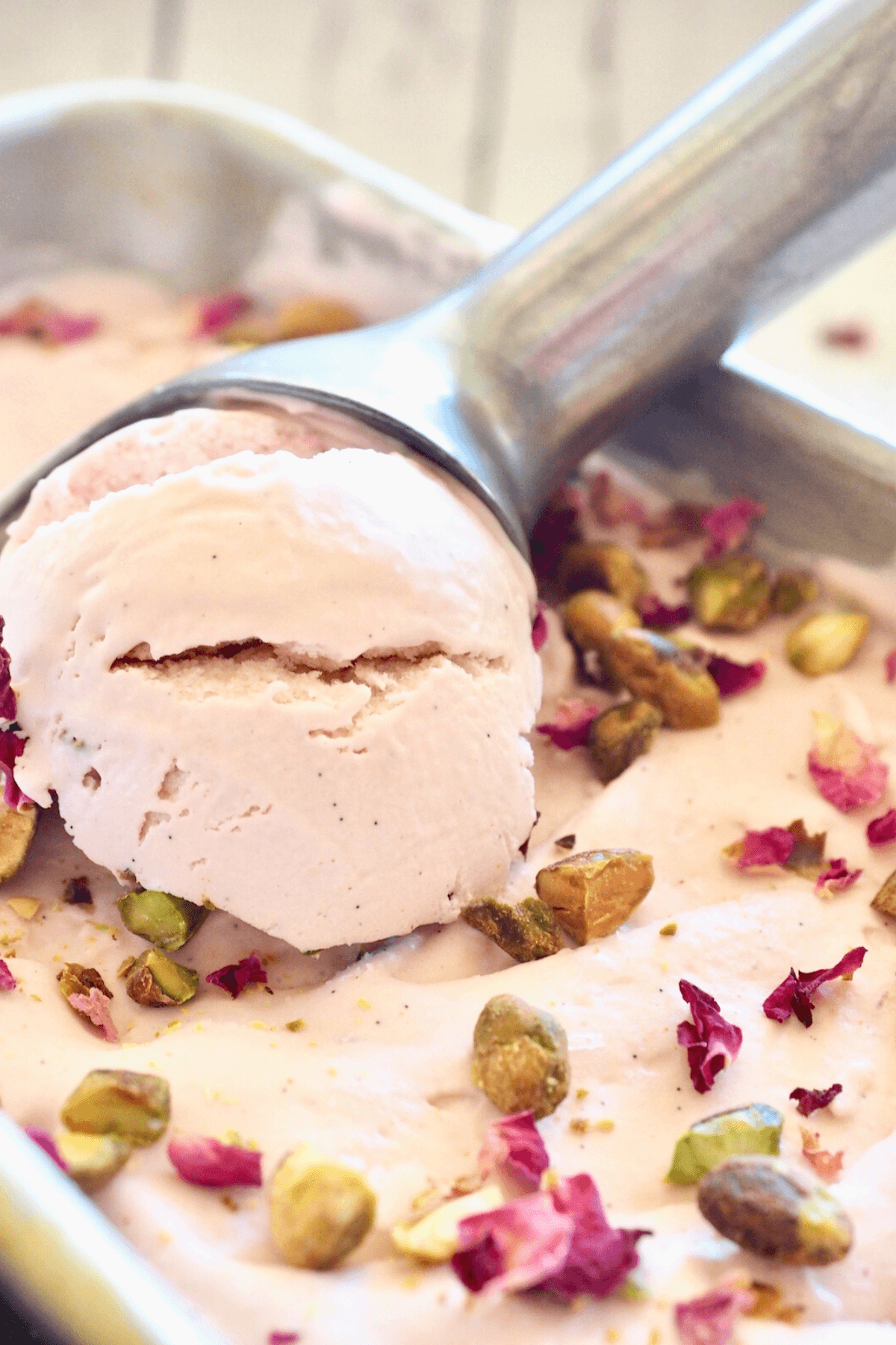 Close up of scooping rose ice cream using an ice cream scoop.