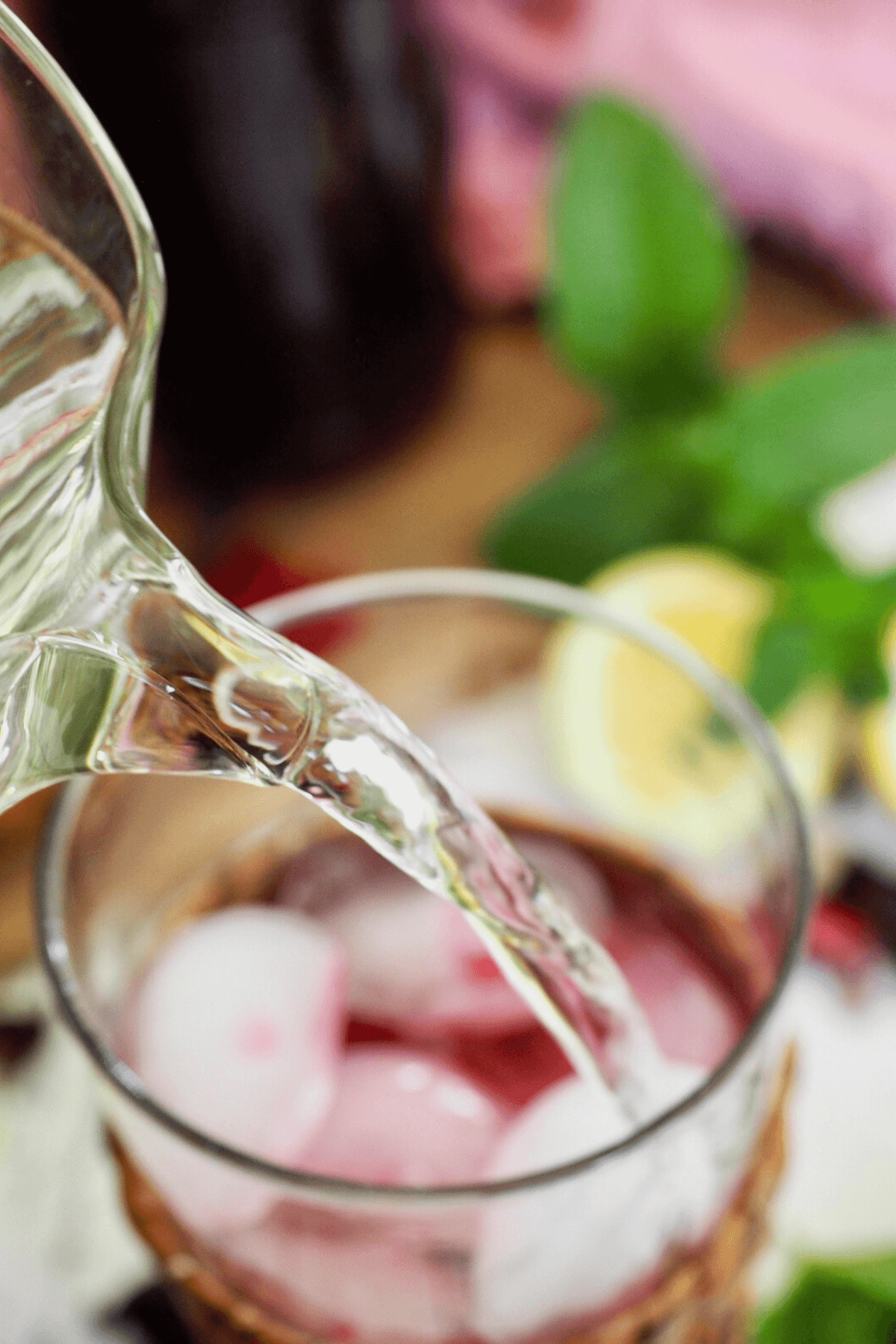 Adding water to glass for passion tea lemonade.