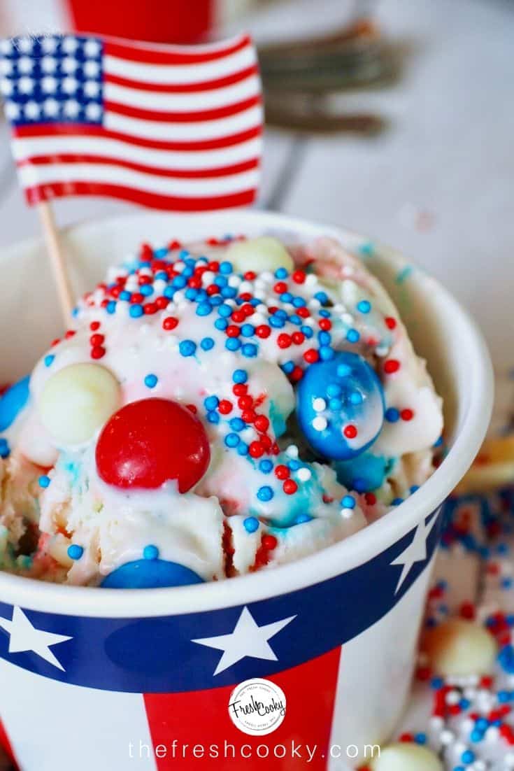 Large scoop of Red, White and Blue M&m no churn ice cream in a patriotic cup with an American flag. 