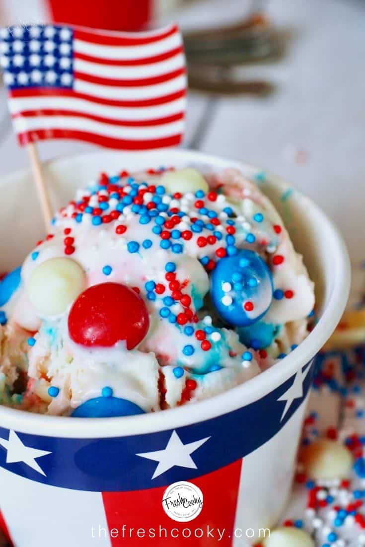 Large scoop of Red, White and Blue M&m no churn ice cream in a patriotic cup with an American flag.