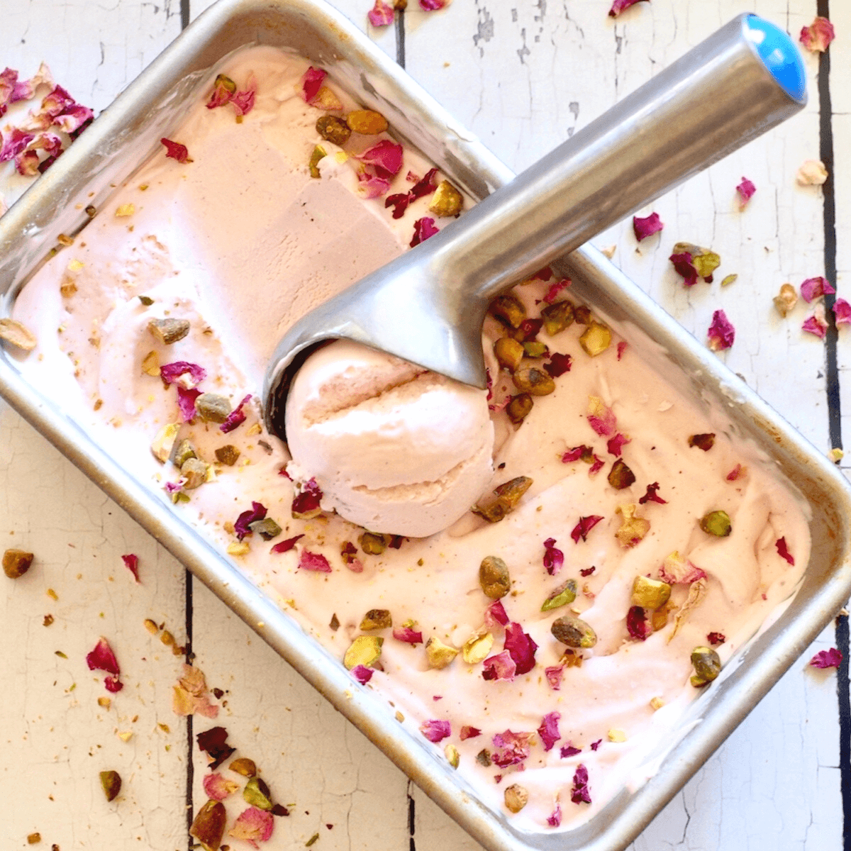 Rose No churn Ice cream square image with pan filled with pink ice cream topped with rose petals and pistachios.