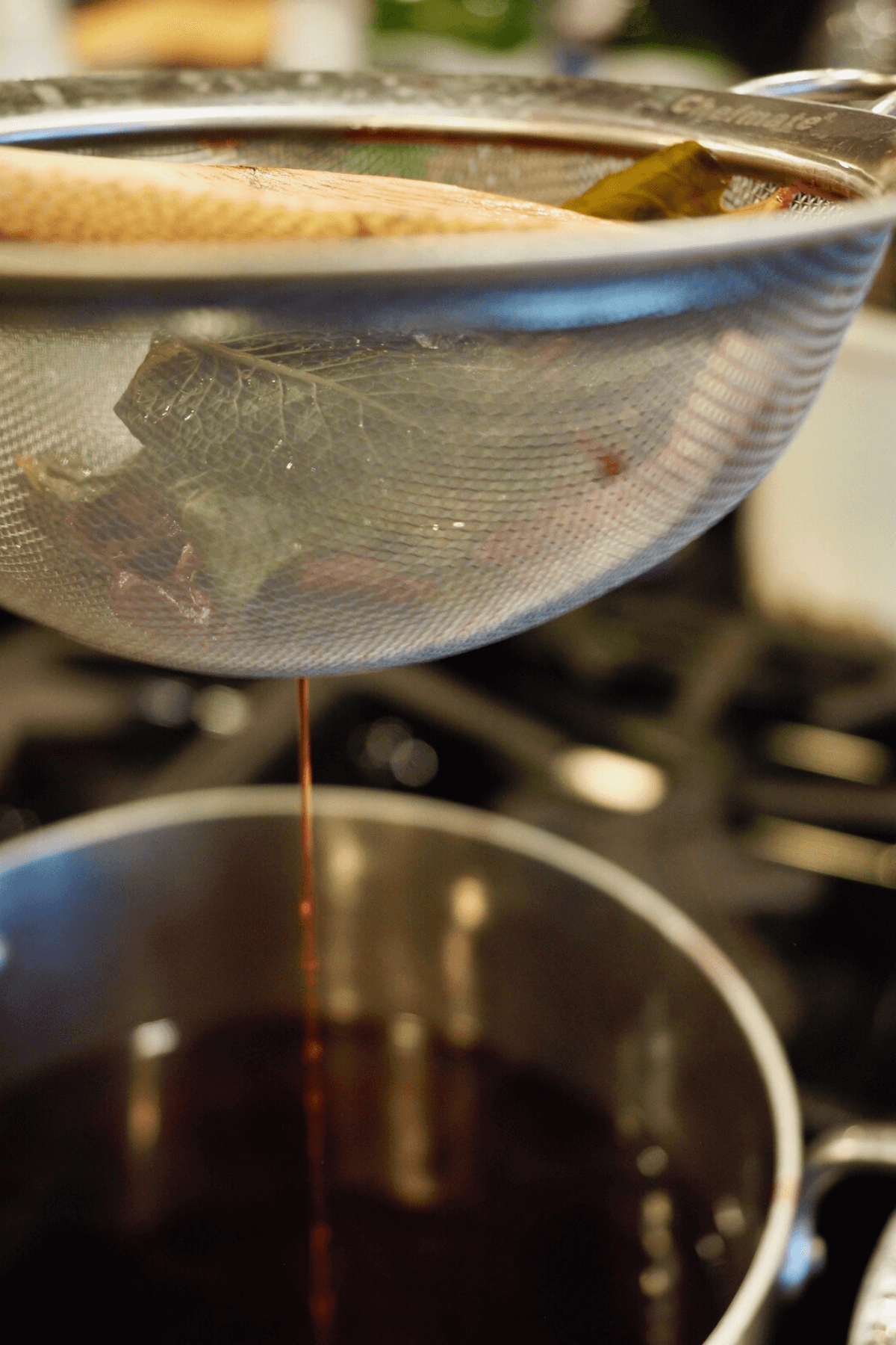 Straining the mint and tea bags from the tea for passion tea lemonade. 