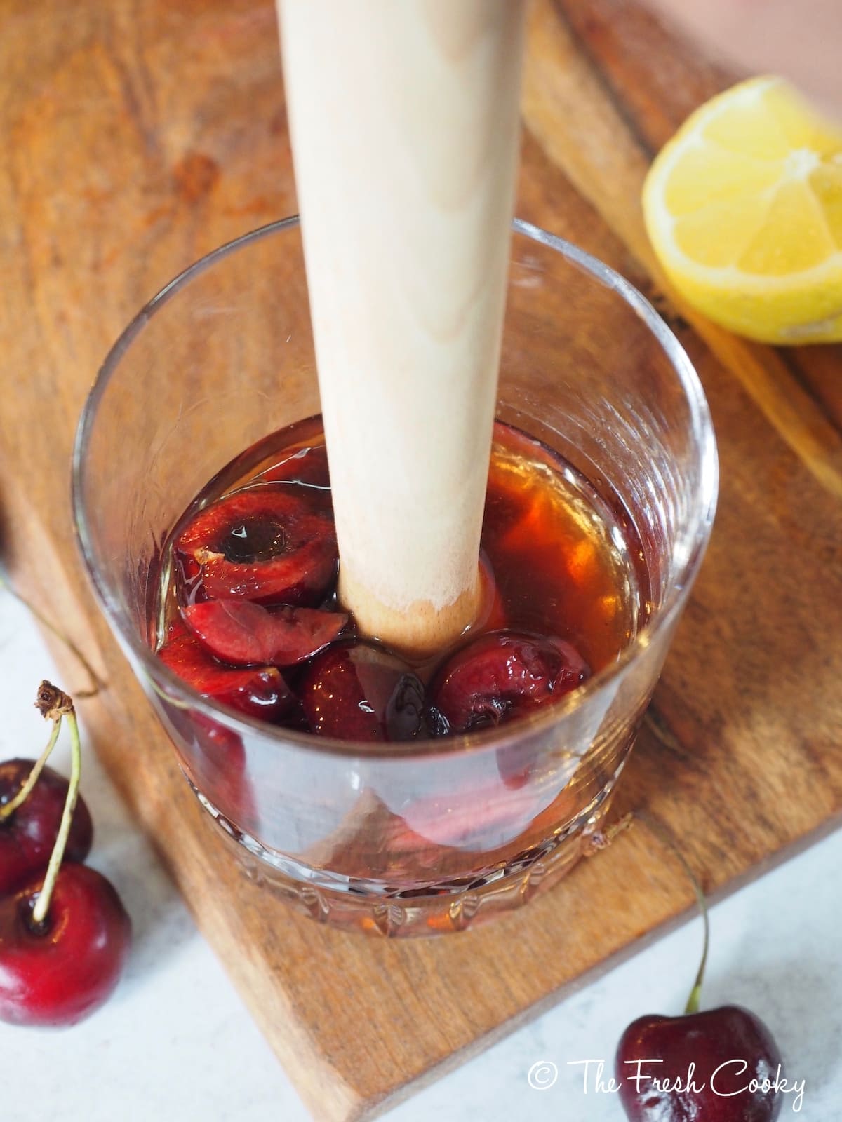 Using a muddler to press the juice out of the fresh cherries for Cherry Bomb Cocktail.