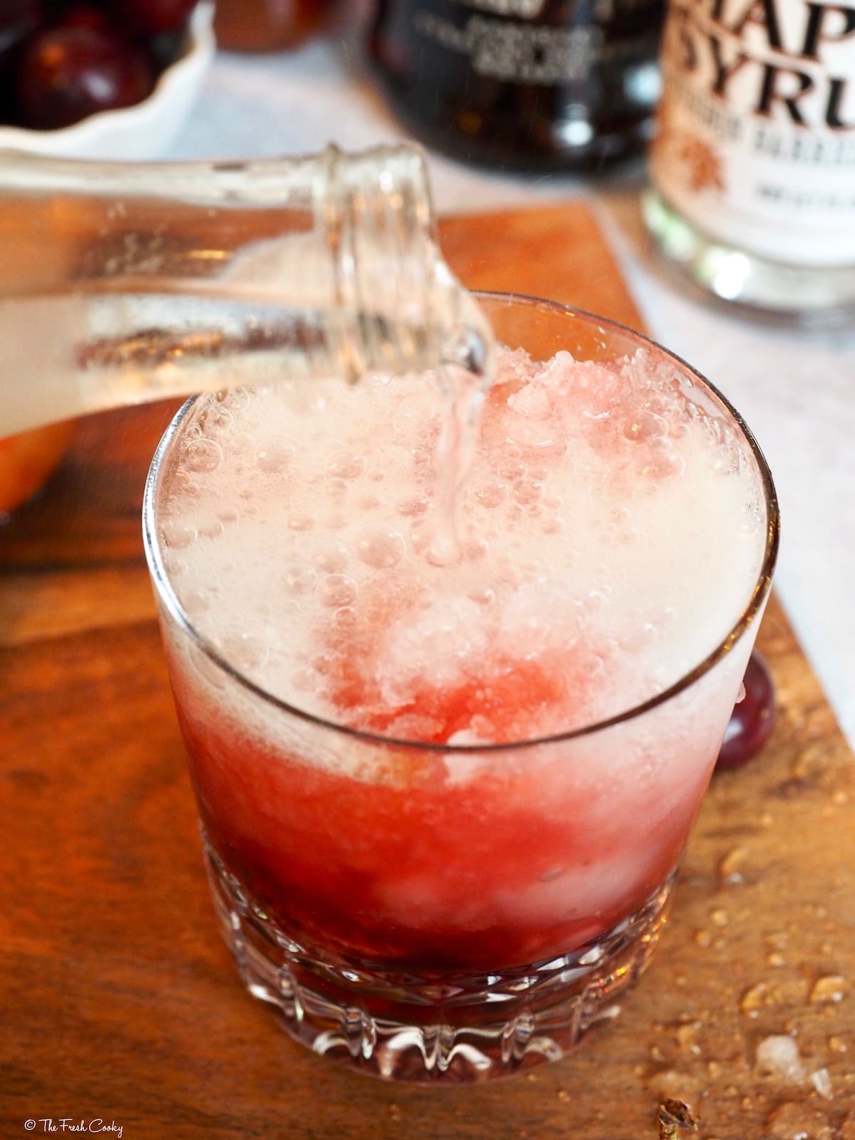 Pouring in a splash of club soda to the Cherry Bomb cocktail. 