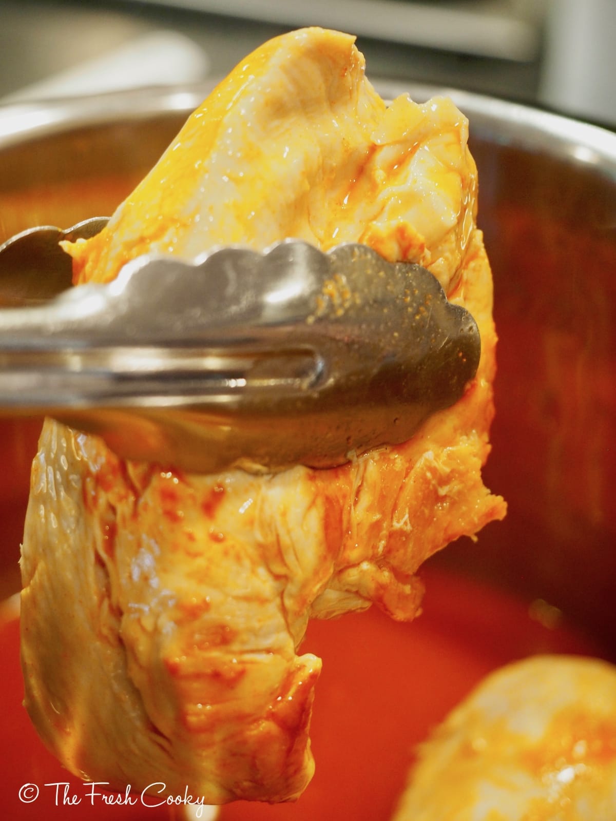 cooked chicken with buffalo wing sauce being pulled out of instant pot. | thefreshcooky.com