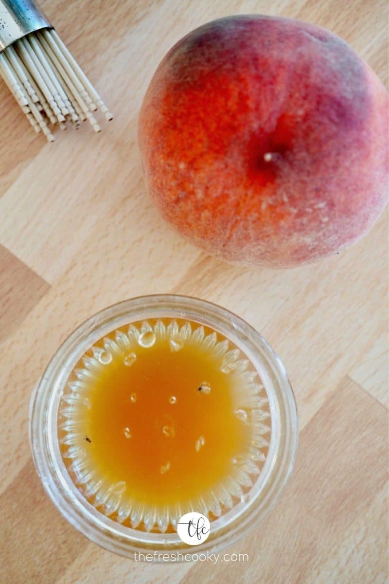 Easy Effective Fruit Fly Trap with trap and peach nearby with wooden toothpicks.