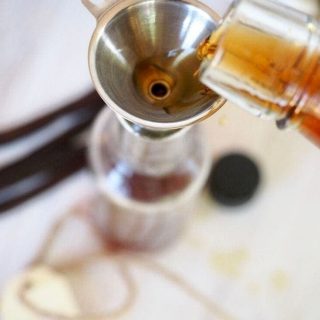 pouring bourbon in bottle for homemade bourbon vanilla extract | thefreshcooky.com