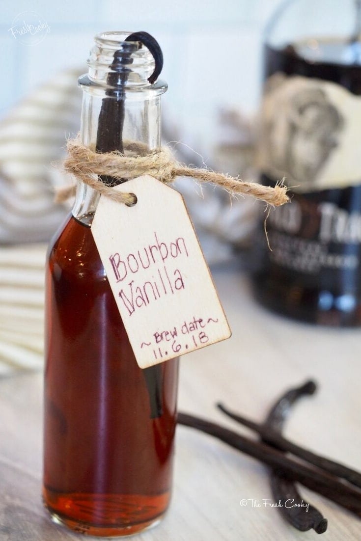 fresh, homemade bottle of bourbon vanilla extract with vanilla bean on rim of bottle | thefreshcooky.com