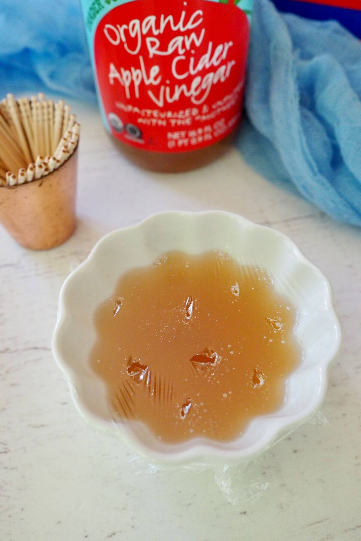 Holes poked into plastic wrap covered bowl of apple cider vinegar to catch fruit flies and gnats.