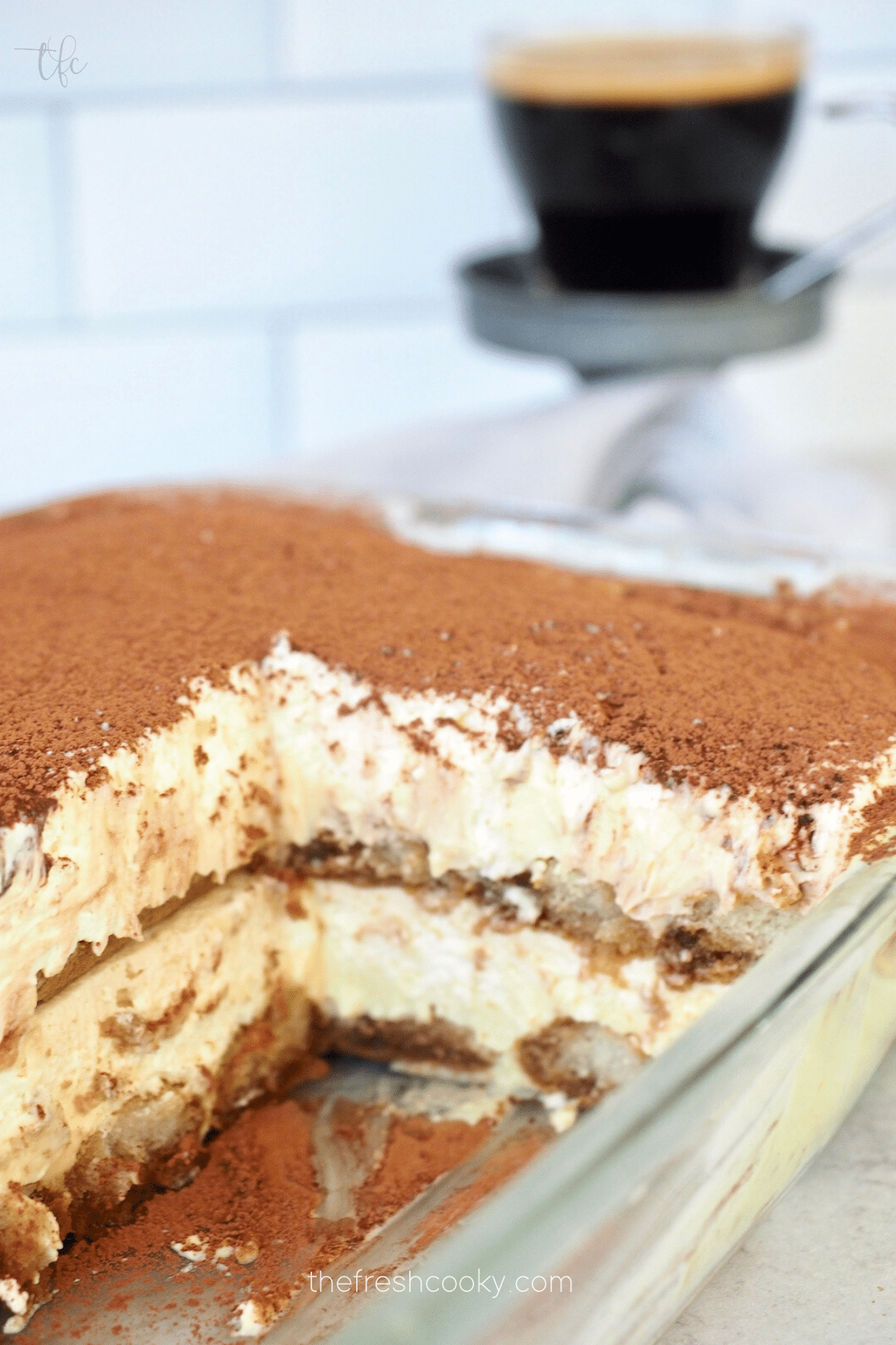 Cross section of layered traditional tiramisu Italian dessert in glass dish.