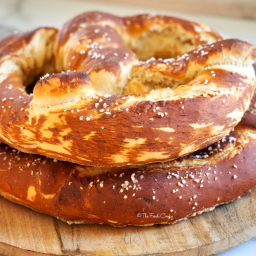 Bavarian Pretzels or Laugenbrezels stacked on top of one another on a wooden platter.