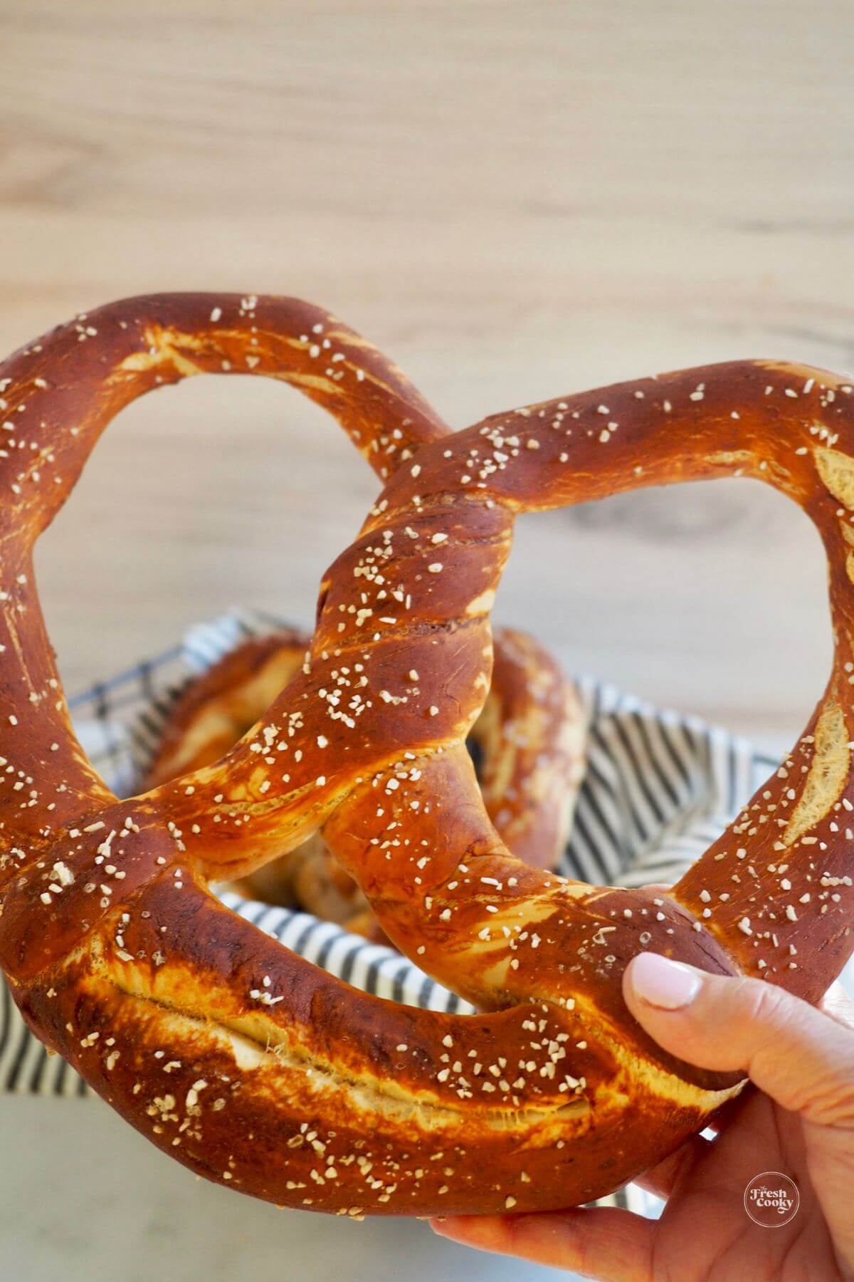 Hand holding giant soft pretzel.
