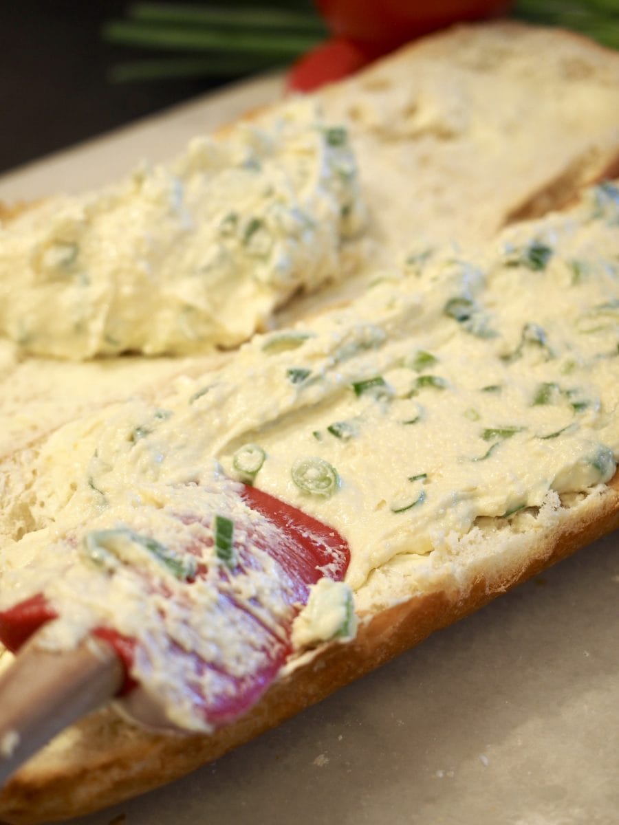 spreading cheesy spread on french bread | thefreshcooky.com